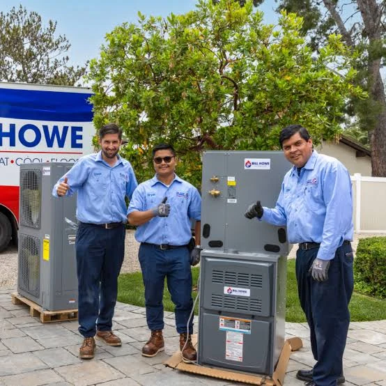 Three technicians standing beside heating and cooling equipment